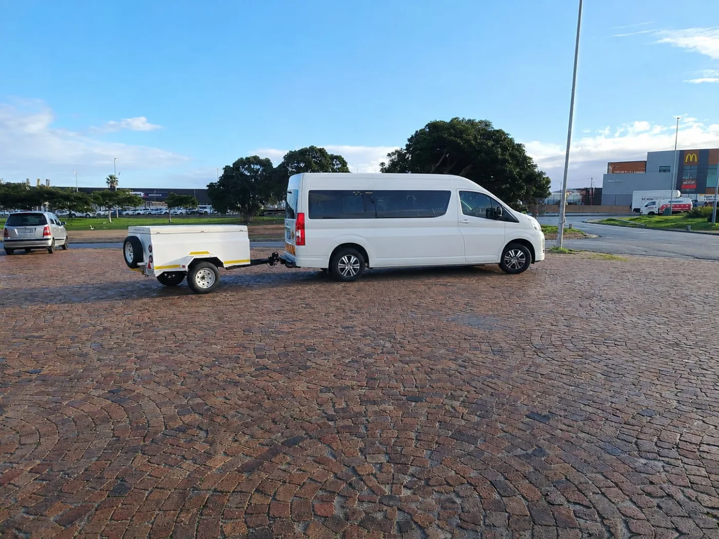 White shuttle minibus with a luggage trailer at the Green Point pickup point