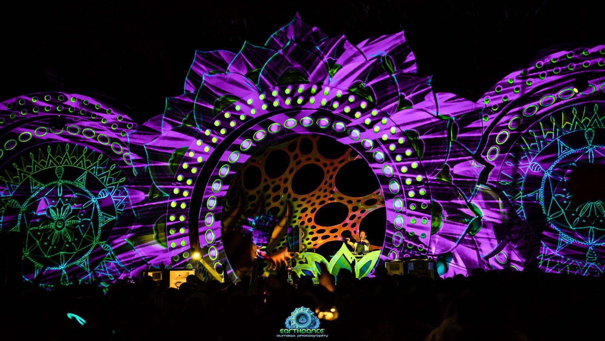 The Earthdance main stage lit up at night in ultraviolet purple and green