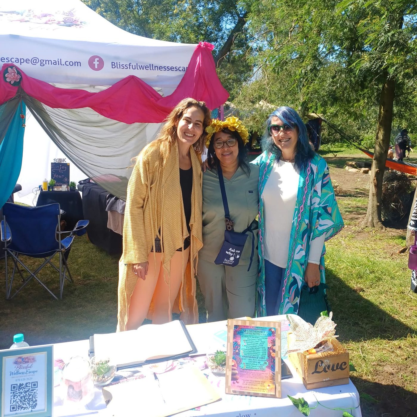 Three Blissful Wellness Escape team members smiling in front of the stall