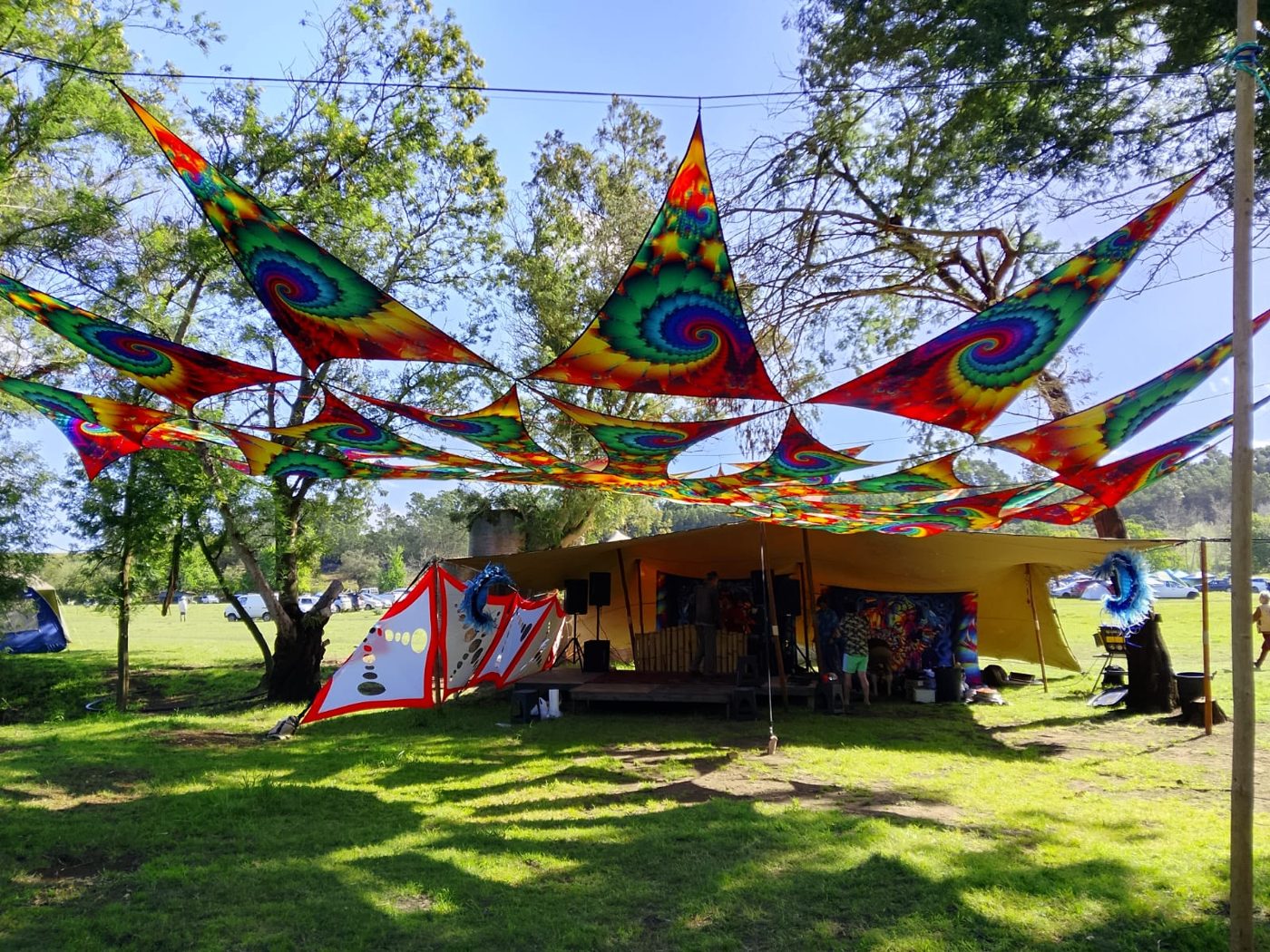 Tie-dye shade sails strung through the trees above the chill space