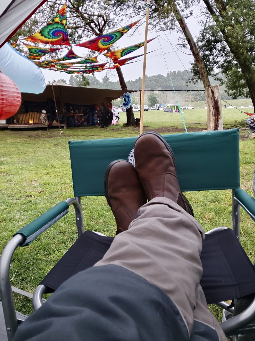 Boots up on a camp chair, looking out from Chill and Charge across the field