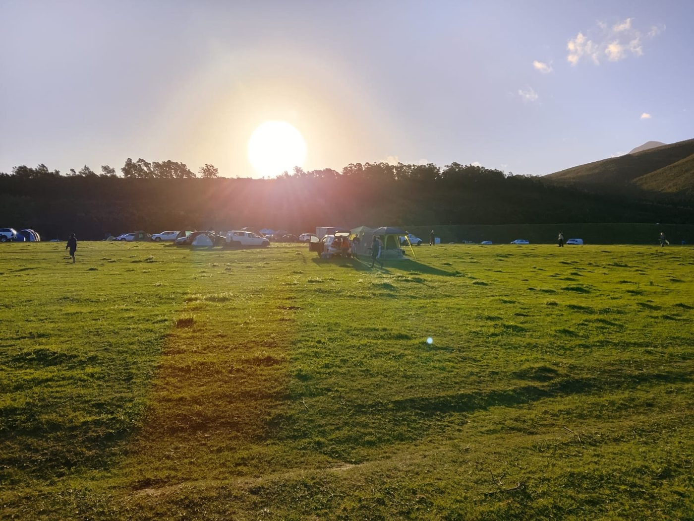 The sun low over the campsite and the open field