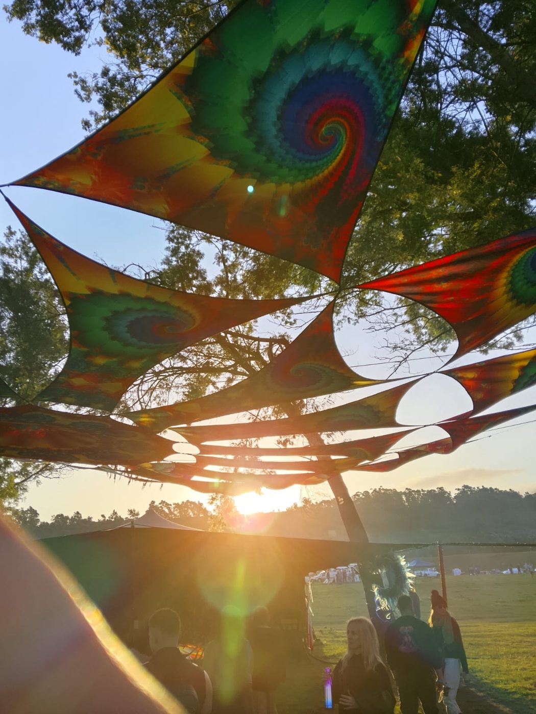 Low sun flaring through the tie-dye shade sails at the end of the day