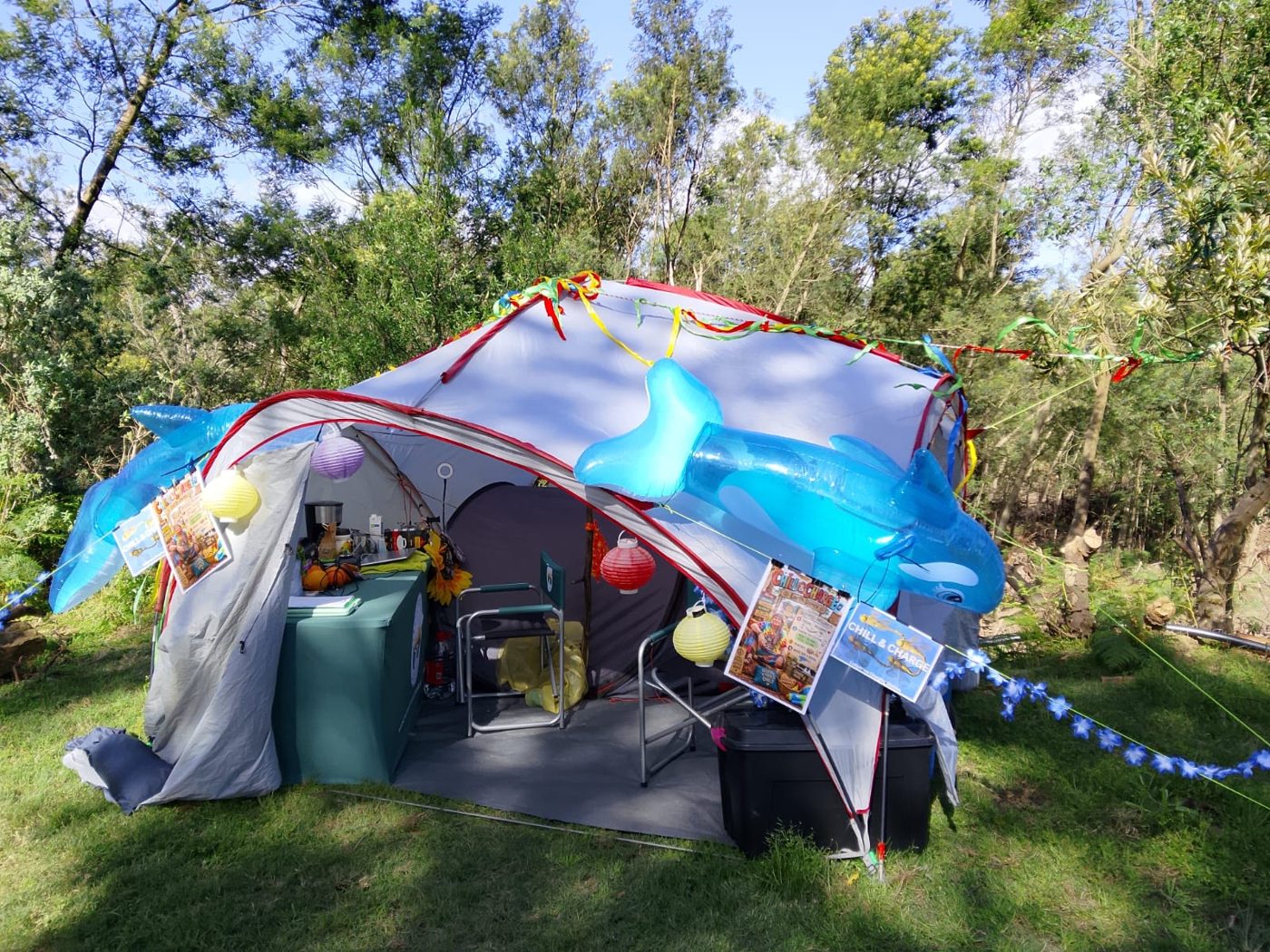 The Chill and Charge tent under the trees, hung with inflatable dolphins, lanterns and bunting