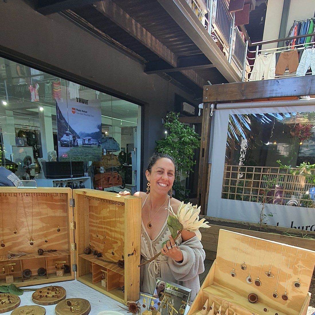 Earth Stories maker Keshia Lee Codron smiling behind her stall, holding a protea flower