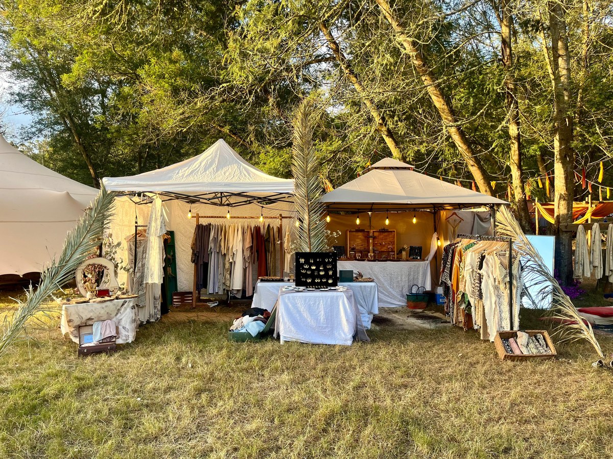 The Earth Stories stall at golden hour, twin tents strung with lights, clothing racks and jewellery displays