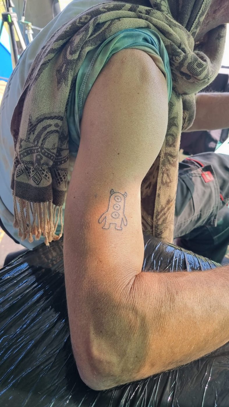 A small linework character tattoo on an upper arm