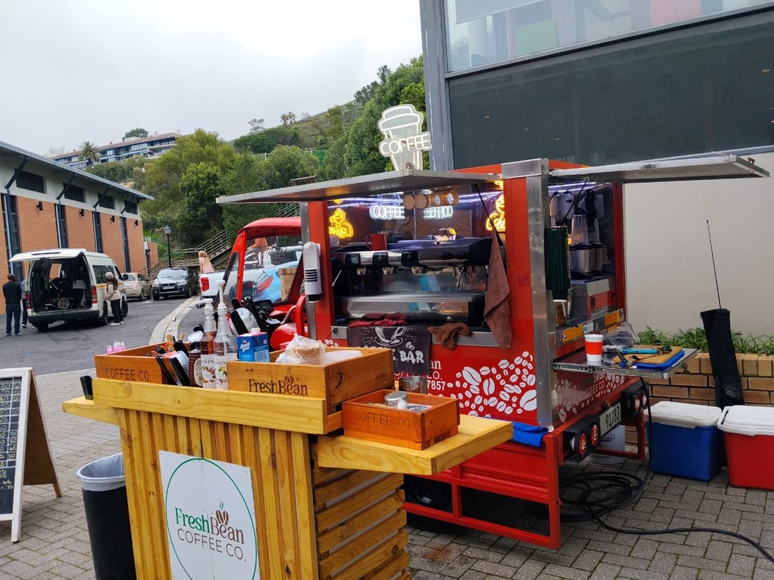 The coffee cart lit up at night with a neon Coffee sign