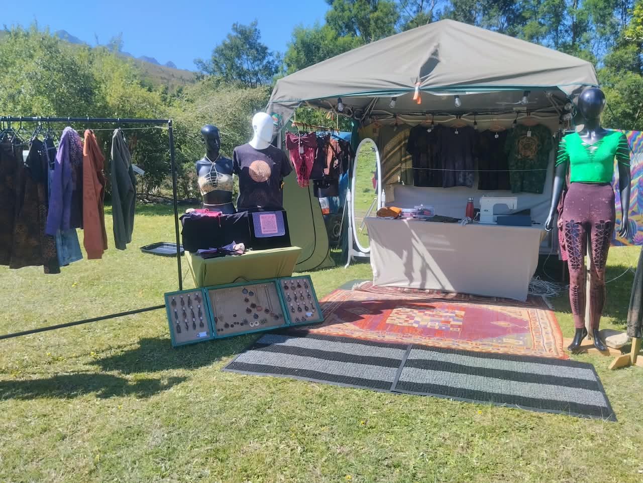 The stall from the front, with rails of upcycled clothing and mannequins under a canvas gazebo