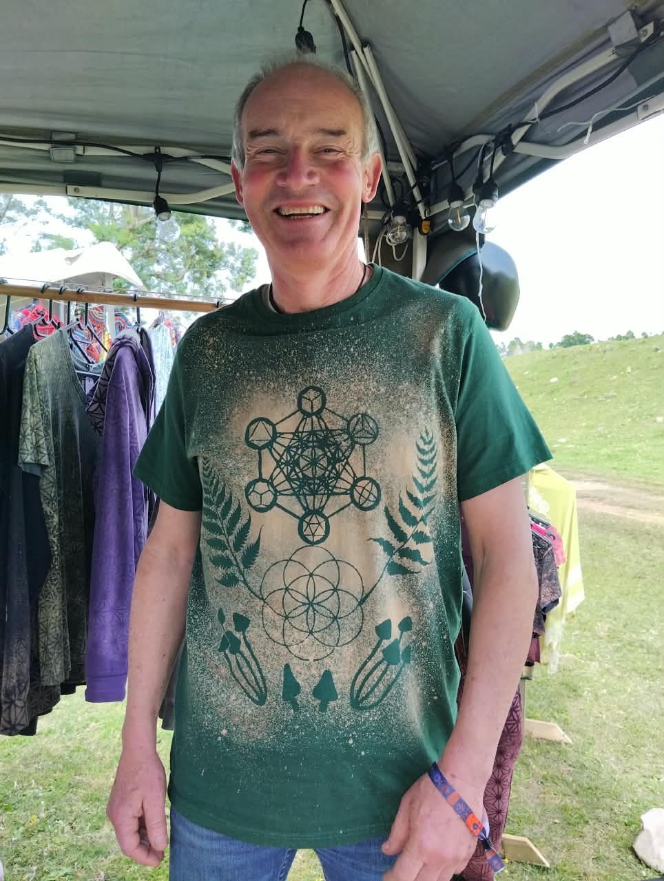 A man smiling in a green bleach-art t-shirt printed with sacred geometry