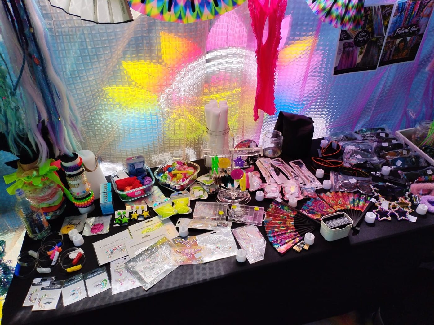 Glow bracelets, face gems, fans and star-shaped glasses laid out on the accessories table