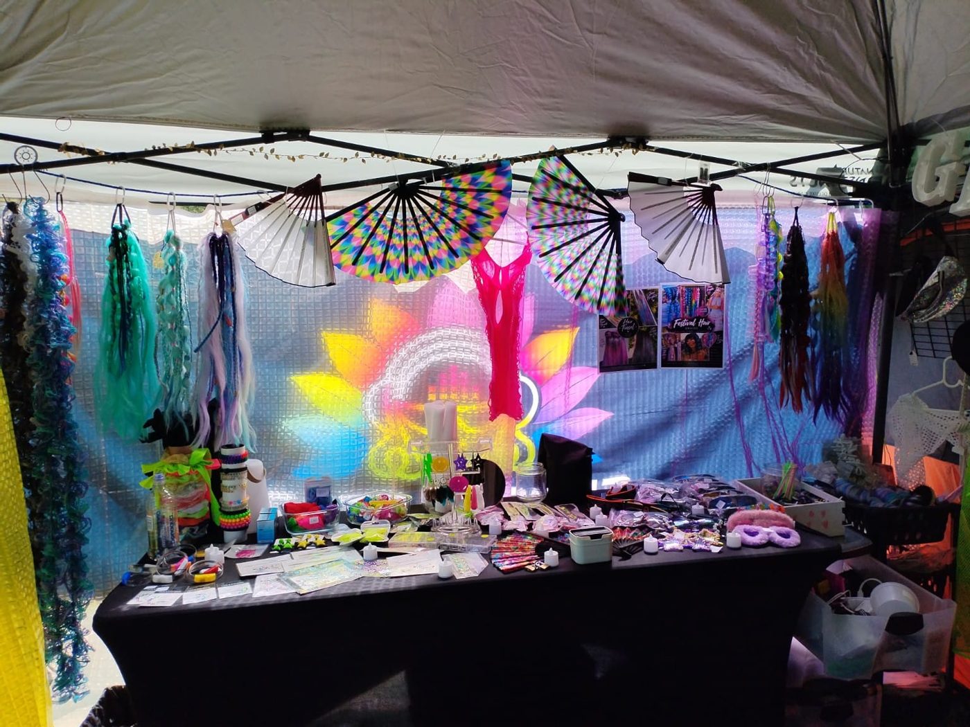 Rainbow fans, braid extensions and a table of festival accessories inside the Groove Gear stall