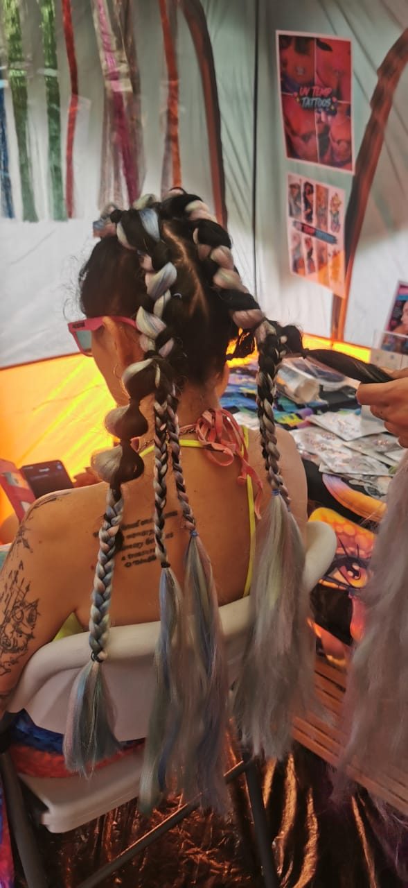 A festival-goer seen from behind with freshly done silver and black festival braids