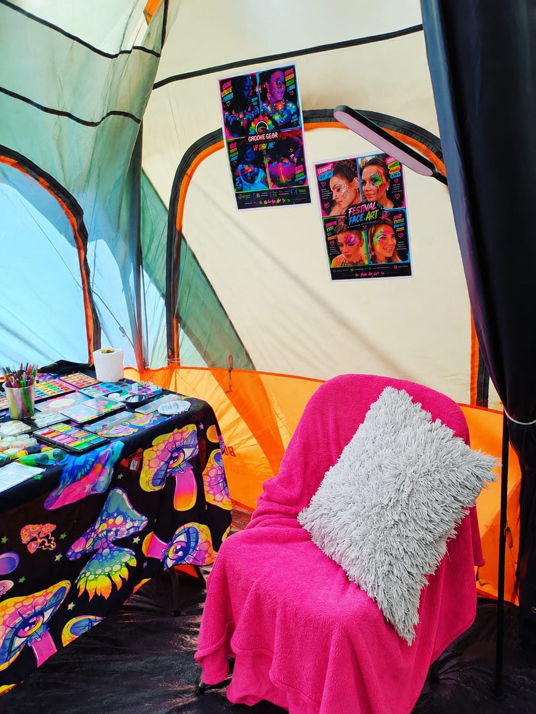A pink-covered lounge chair beside the face paint table inside the Groove Gear lounge