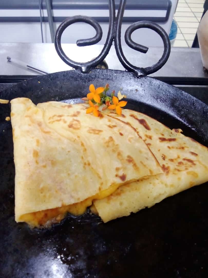 A folded pancake on the grill, garnished with an edible flower