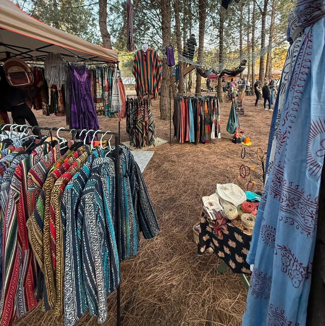 The Wild & Woven stall, with racks of natural-fibre clothing among the pine trees